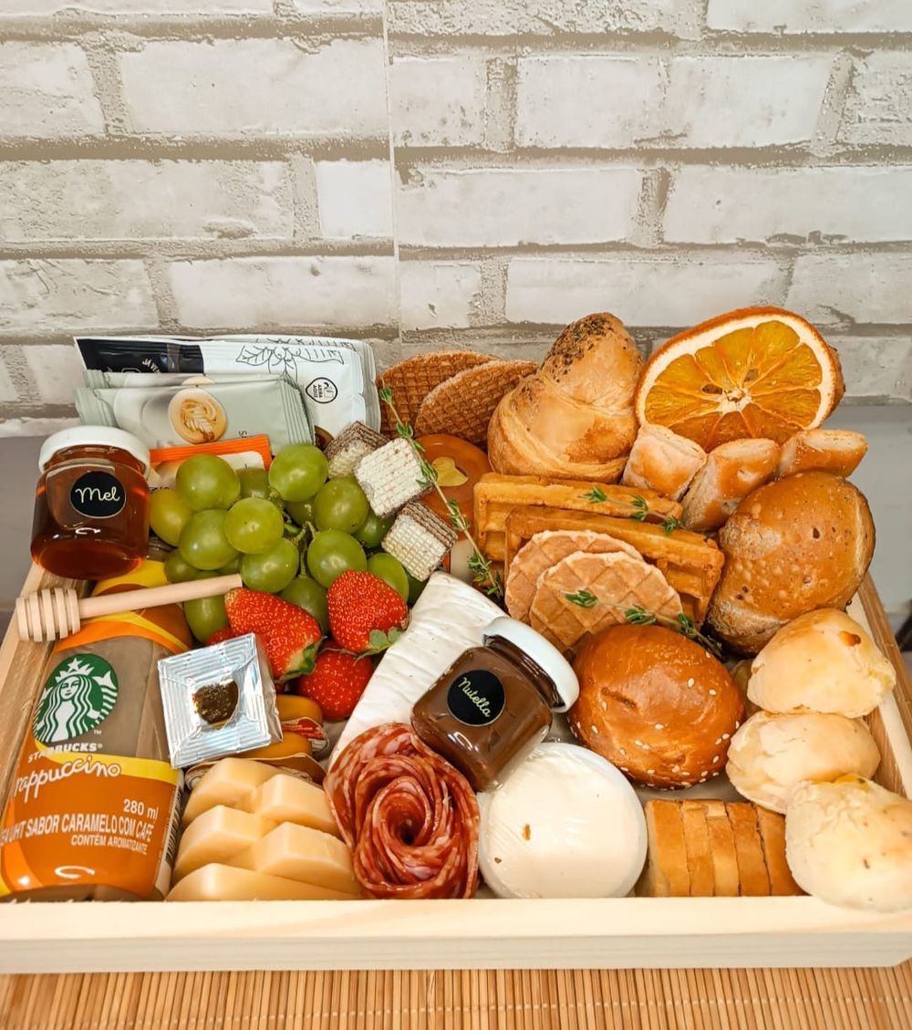 Cesta de café da manhã com pães, frutas, frios e cappuccino